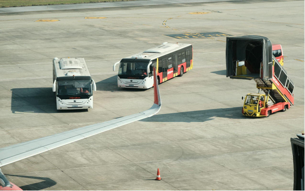 Airport tarmac with shuttle buses and a baggage loader.