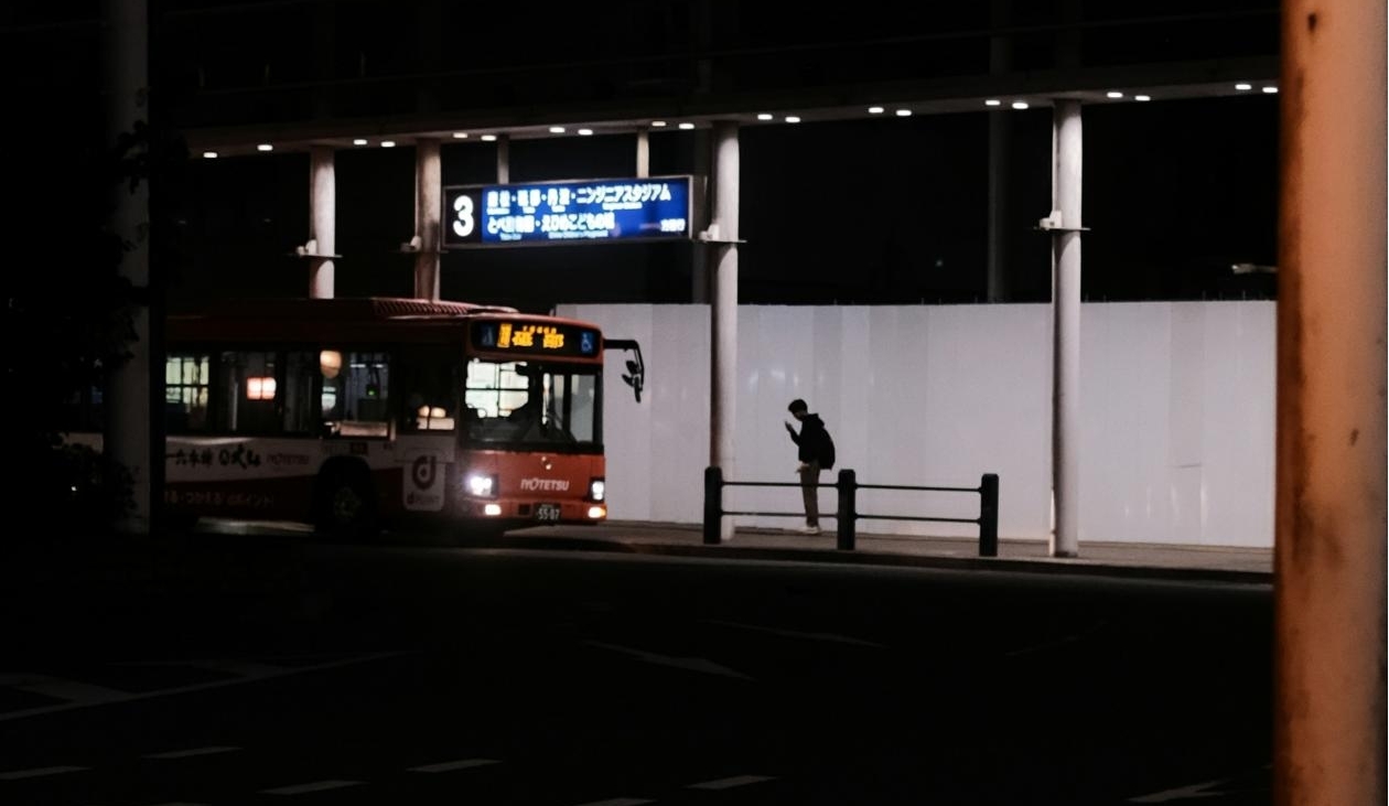 Person waiting for bus at night